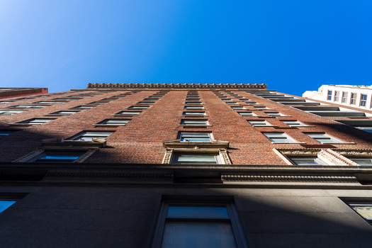 Manhattan United States 03 December 2025 View of a towering brick building reaching towards the clear blue sky its windows reflecting the sunlight in a mesmerizing pattern.