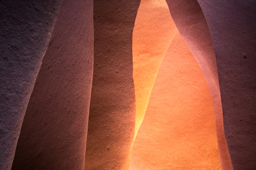 View of sculpted sandstone walls glow with warm ethereal light casting soft shadows and revealing intricate textures in Escalante Utah United States.