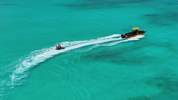 Aerial view of a yellow boat towing a person on an inflatable tube Maldives. Aerial view of a yellow boat towing a person on an inflatable tube Maldives.