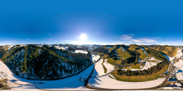 Aerial view of the village of Trueb nestled among snow covered hills and dense evergreen forests under a bright winter sun in Emmental Bern Switzerland. Aerial view of the village of Trueb nestled among snow covered hills and dense evergreen forests under a bright winter sun in Emmental Bern Switzerland.