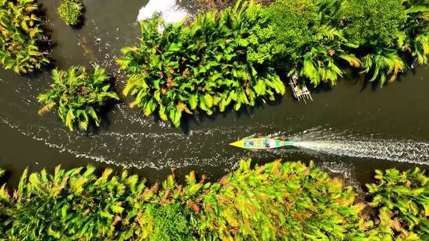 Aerial view of a boat cruising through a lush palm river in Maros Indonesia. Aerial view of a boat cruising through a lush palm river in Maros Indonesia.