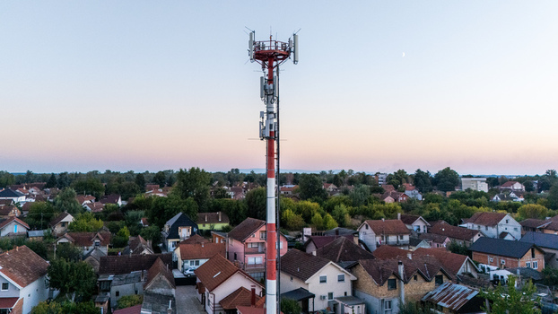 Aerial view of a telecommunications tower rising above the residential rooftops and lush trees in Sremska Mitrovica Vojvodina Serbia.