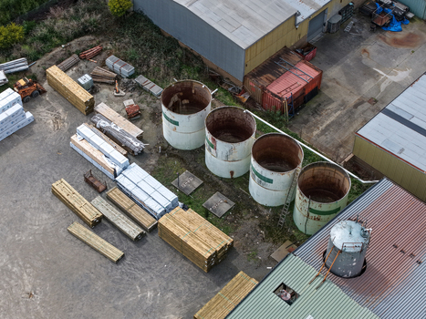 Melbourne Australia 25 September 2026 Aerial view of an industrial site featuring large cylindrical storage tanks stacks of timber and various machinery in a factory yard.