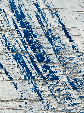 View of peeling blue paint streaks dramatically down a weathered white wooden surface a study in texture and decay De Cocksdorp Noord Holland Netherlands. View of peeling blue paint streaks dramatically down a weathered white wooden surface a study in texture and decay De Cocksdorp Noord Holland Netherlands.