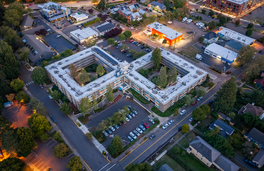 Aerial view of a large multi story building complex with two internal courtyards surrounding parking lots and urban streets in Eugene Oregon United States. Aerial view of a large multi story building complex with two internal courtyards surrounding parking lots and urban streets in Eugene Oregon United States.