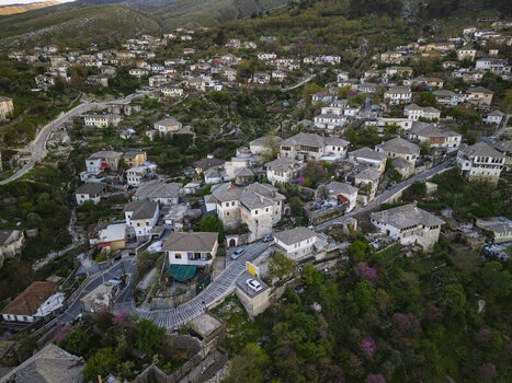 Aerial view of Gjirokaster featuring historic stone houses with slate roofs and winding streets nestled in the mountainous landscape of Gjirokaster Gjirokaster County Albania. Aerial view of Gjirokaster featuring historic stone houses with slate roofs and winding streets nestled in the mountainous landscape of Gjirokaster Gjirokaster County Albania.