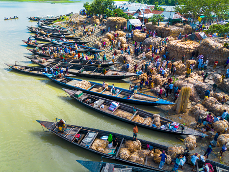 Islampur Bangladesh 05 September 2025 Aerial view of traditional wooden boats docked along a busy riverbank where workers are loading large bundles of jute under a bright sun. Islampur Bangladesh 05 September 2025 Aerial view of traditional wooden boats docked along a busy riverbank where workers are loading large bundles of jute under a bright sun.