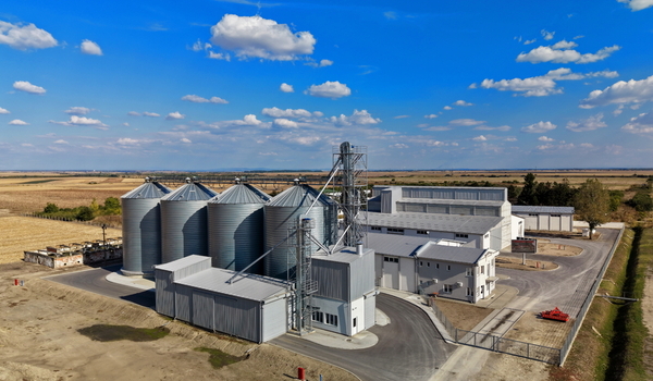 Aerial view of storage silo Bavaniste with metallic grain bins and industrial buildings surrounded by agricultural fields under a blue sky in Bavaniste Vojvodina Serbia.
