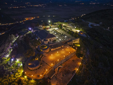 Aerial view of the illuminated Lekuresi Castle at night featuring historic stone walls courtyards and surrounding landscape in Saranda Vlore County Albania. Aerial view of the illuminated Lekuresi Castle at night featuring historic stone walls courtyards and surrounding landscape in Saranda Vlore County Albania.