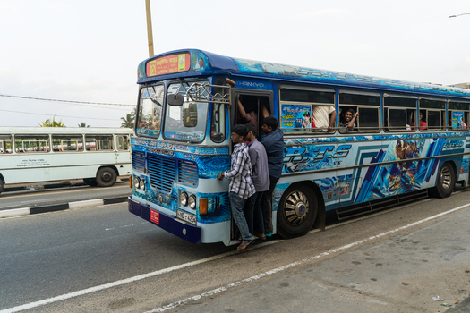 Sri Lanka 15 January 2026 View of a crowded blue public bus traveling between Colombo and Galle with passengers hanging from the door.
