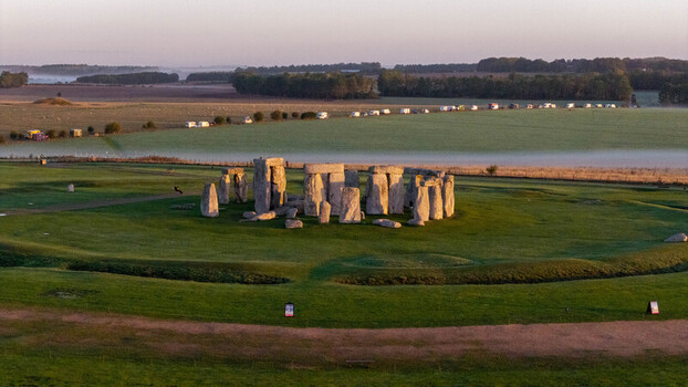 Aerial view of Stonehenge standing in a grassy field during the golden hour with soft morning mist over the surrounding landscape in Salisbury England United Kingdom. Aerial view of Stonehenge standing in a grassy field during the golden hour with soft morning mist over the surrounding landscape in Salisbury England United Kingdom.