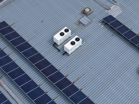 Aerial view of solar panels and HVAC units installed on a corrugated metal industrial roof in Melbourne VIC Australia.