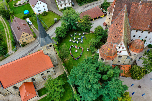 Wiesenthau Germany 02 May 2026 Aerial view of Schloss Wiesenthau and the local church with people standing in a heart shape on a green lawn between historic buildings. Wiesenthau Germany 02 May 2026 Aerial view of Schloss Wiesenthau and the local church with people standing in a heart shape on a green lawn between historic buildings.
