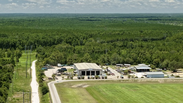 Aerial view of the Putnam County Central Landfill and Waste Pro facility featuring maintenance buildings parked trucks and surrounding dense forest in Palatka Florida United States.