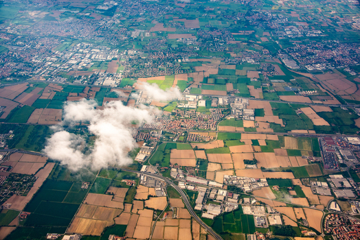 Aerial view of the agricultural landscape and suburban outskirts near Bologna featuring patchwork fields roads and buildings under a partly cloudy sky in Bologna Emilia Romagna Italy. Aerial view of the agricultural landscape and suburban outskirts near Bologna featuring patchwork fields roads and buildings under a partly cloudy sky in Bologna Emilia Romagna Italy.