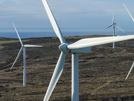 Aerial view of wind turbines standing on a coastal hillside with the blue sea in the background in Scotland United Kingdom. Aerial view of wind turbines standing on a coastal hillside with the blue sea in the background in Scotland United Kingdom.