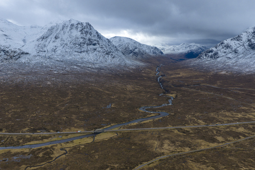 Aerial view of River Etive Bridge crossing the winding river amidst snow capped mountains and brown moorland in Ballachulish Scotland United Kingdom. Aerial view of River Etive Bridge crossing the winding river amidst snow capped mountains and brown moorland in Ballachulish Scotland United Kingdom.
