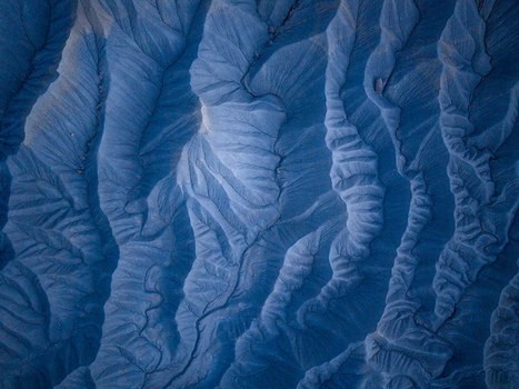 Aerial view of the intricate eroded blue toned badlands landscape with deep ridges and natural drainage patterns in Caineville Utah United States. Aerial view of the intricate eroded blue toned badlands landscape with deep ridges and natural drainage patterns in Caineville Utah United States.