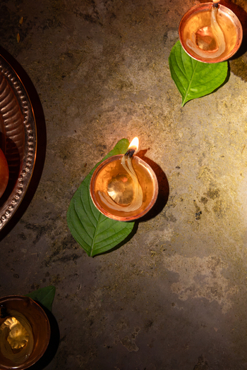 View of traditional oil lamps glowing on green leaves during a ceremony in Kathmandu Bagmati Province Nepal.