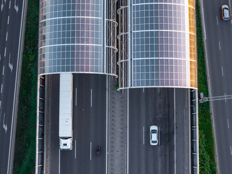 Aerial view of Trasa Torunska highway featuring modern solar panel roof structures over the lanes with trucks and cars driving below in Warszawa Mazowieckie Poland. Aerial view of Trasa Torunska highway featuring modern solar panel roof structures over the lanes with trucks and cars driving below in Warszawa Mazowieckie Poland.