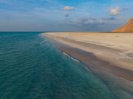 Aerial view of turquoise waters meet the sandy shore under a serene sky near the Qalanciya lagoon Qalanciya Socotra Yemen.