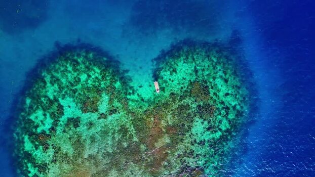 Aerial view of a heart shaped coral reef and a small boat Honduras. Aerial view of a heart shaped coral reef and a small boat Honduras.