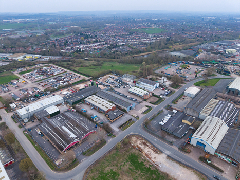 Aerial view of industrial buildings casting long shadows on the asphalt juxtaposed against verdant fields and distant residential areas Coventry United Kingdom. Aerial view of industrial buildings casting long shadows on the asphalt juxtaposed against verdant fields and distant residential areas Coventry United Kingdom.