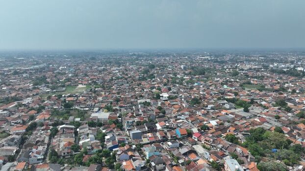 Aerial view of a dense residential neighborhood with terracotta rooftops narrow streets and lush green trees in Kasemen Banten Indonesia. Aerial view of a dense residential neighborhood with terracotta rooftops narrow streets and lush green trees in Kasemen Banten Indonesia.