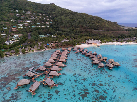 Aerial view of Sofitel Kia Ora Moorea Beach Resort with overwater bungalows in the turquoise lagoon coral reefs and lush mountains in Moorea Maiao Windward Islands French Polynesia. Aerial view of Sofitel Kia Ora Moorea Beach Resort with overwater bungalows in the turquoise lagoon coral reefs and lush mountains in Moorea Maiao Windward Islands French Polynesia.