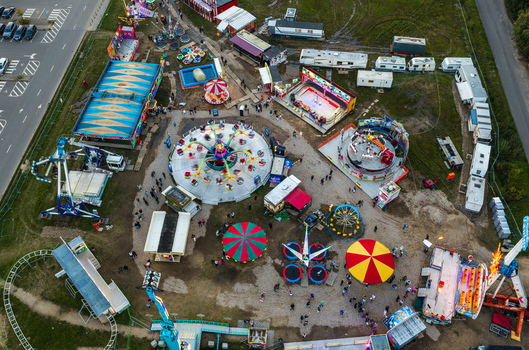 Aerial view of a colorful carnival fairground with various amusement rides spinning attractions and food stalls set up in an open field in Vilnius Vilnius County Lithuania. Aerial view of a colorful carnival fairground with various amusement rides spinning attractions and food stalls set up in an open field in Vilnius Vilnius County Lithuania.