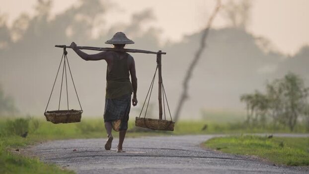 View of a worker carrying baskets on a rural road Bangladesh.