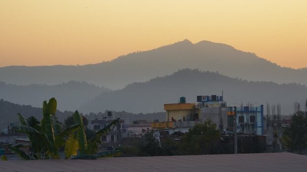 View of hazy mountain peaks and urban rooftops at sunset Nepal.