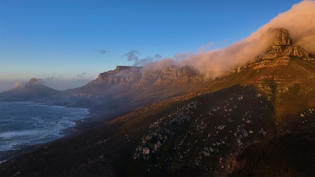 Aerial view of Table Mountain and the Twelve Apostles mountain range with clouds rolling over the peaks during golden hour in Cape Town Western Cape South Africa. Aerial view of Table Mountain and the Twelve Apostles mountain range with clouds rolling over the peaks during golden hour in Cape Town Western Cape South Africa.