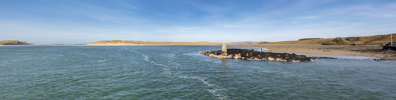 Aerial view of Ballyness Bay with its sandy shores tidal waters and a small rocky outcrop featuring a navigational marker under a clear blue sky in Ballyness County Donegal Ireland. Aerial view of Ballyness Bay with its sandy shores tidal waters and a small rocky outcrop featuring a navigational marker under a clear blue sky in Ballyness County Donegal Ireland.