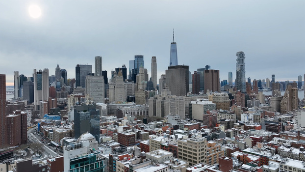 Aerial view of the Manhattan skyline featuring One World Trade Center and snow covered rooftops under an overcast sky in New York New York United States. Aerial view of the Manhattan skyline featuring One World Trade Center and snow covered rooftops under an overcast sky in New York New York United States.