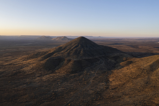 Aerial view of rugged sun kissed mountain peaks rise dramatically from the arid landscape casting long shadows under a vast open sky Windhoek Namibia. Aerial view of rugged sun kissed mountain peaks rise dramatically from the arid landscape casting long shadows under a vast open sky Windhoek Namibia.