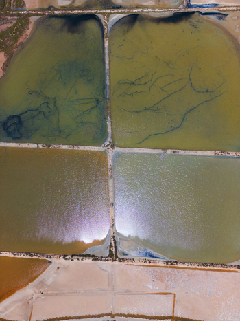 Aerial view of Salines des Trenc salt evaporation ponds with geometric dikes and shimmering water surfaces in Campos Islas Baleares Spain. Aerial view of Salines des Trenc salt evaporation ponds with geometric dikes and shimmering water surfaces in Campos Islas Baleares Spain.