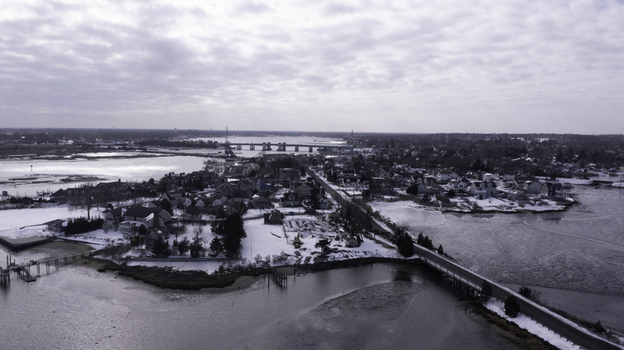 Aerial view of snow covered residential areas frozen waterways and a bridge in the coastal town of Manasquan New Jersey United States. Aerial view of snow covered residential areas frozen waterways and a bridge in the coastal town of Manasquan New Jersey United States.