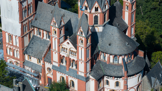 Aerial view of Limburg Cathedral with its distinctive red and white Romanesque architecture slate roofs and multiple towers surrounded by greenery in Limburg an der Lahn Hessen Germany. Aerial view of Limburg Cathedral with its distinctive red and white Romanesque architecture slate roofs and multiple towers surrounded by greenery in Limburg an der Lahn Hessen Germany.