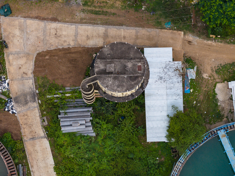 Aerial view of a circular water storage tank and adjacent industrial structures surrounded by lush greenery and concrete pathways in Karad Maharashtra India.