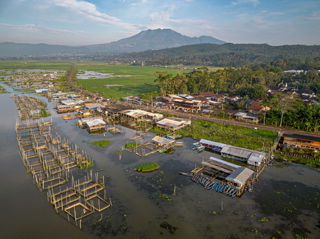 Aerial view of Spot Mancing Sumurup Rawapening featuring traditional fishing platforms and boats on the lake with a mountain backdrop Semarang Regency Central Java Indonesia.