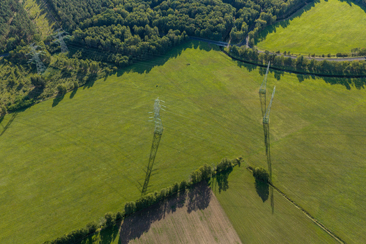 Aerial view of high voltage power lines crossing green agricultural fields and meadows near a forest edge in Peitz Brandenburg Germany. Aerial view of high voltage power lines crossing green agricultural fields and meadows near a forest edge in Peitz Brandenburg Germany.