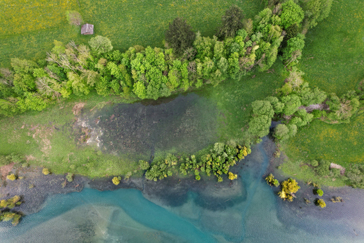 Aerial view of Lac du Vernex featuring turquoise waters and lush green meadows along the shore in Rossiniere Vaud Switzerland.