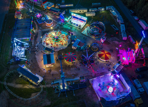 Aerial view of a vibrant night fairground featuring illuminated amusement rides colorful tents and parked trailers under the night sky in Vilnius Vilnius County Lithuania. Aerial view of a vibrant night fairground featuring illuminated amusement rides colorful tents and parked trailers under the night sky in Vilnius Vilnius County Lithuania.