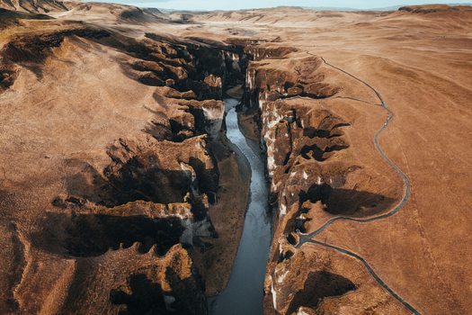 Aerial view of the serpentine river carves through the deep rugged Fjadrargljufur canyon a tapestry of golden hues against the stark Icelandic landscape Fjadrargljufur Iceland. Aerial view of the serpentine river carves through the deep rugged Fjadrargljufur canyon a tapestry of golden hues against the stark Icelandic landscape Fjadrargljufur Iceland.
