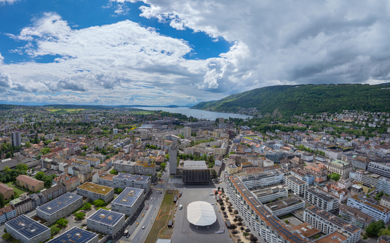Aerial view of Esplanade Kongresshaus 11 surrounded by urban architecture Lake Biel and lush green hills under a cloudy sky Biel Bienne Canton of Bern Switzerland. Aerial view of Esplanade Kongresshaus 11 surrounded by urban architecture Lake Biel and lush green hills under a cloudy sky Biel Bienne Canton of Bern Switzerland.