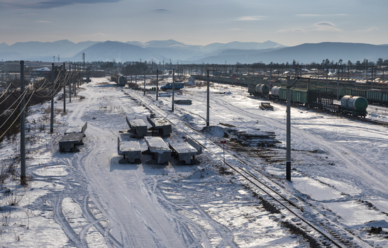 Aerial view of a snow covered railway yard with freight trains concrete sleepers and distant mountains in Severobaykalsk Buryatia Russia.