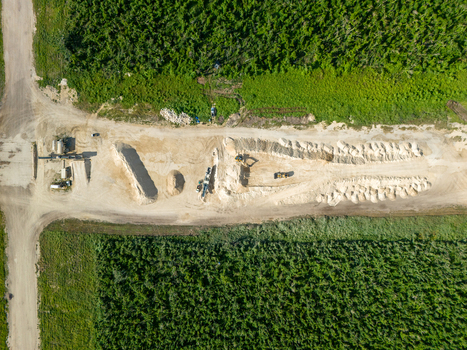 Aerial view of the restoration of North Field Base showing industrial equipment large sand piles and dirt roads in Northern Tinian Tinian Northern Mariana Islands.