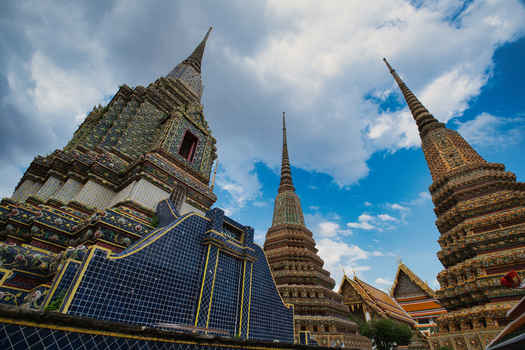 View of the ornate stupas at Wat Phra Chetuphon Wimon Mangkhalaram Rajwaramahawihan with intricate mosaic patterns under a blue sky in Krung Thep Maha Nakhon Thailand. View of the ornate stupas at Wat Phra Chetuphon Wimon Mangkhalaram Rajwaramahawihan with intricate mosaic patterns under a blue sky in Krung Thep Maha Nakhon Thailand.
