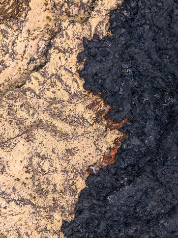 Aerial view of the stark contrast between light colored mossy terrain and dark solidified black lava flow in the volcanic landscape of Iceland. Aerial view of the stark contrast between light colored mossy terrain and dark solidified black lava flow in the volcanic landscape of Iceland.